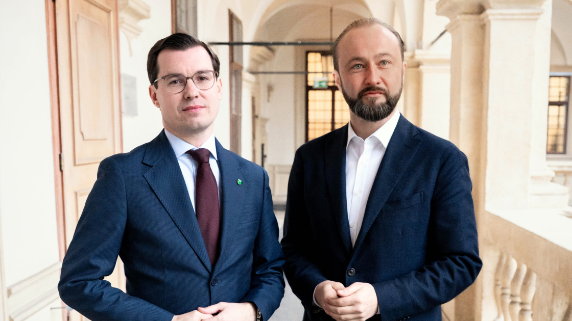 Werner Kogler und Robert Habeck stehen in einem Arkadengang in Wien.